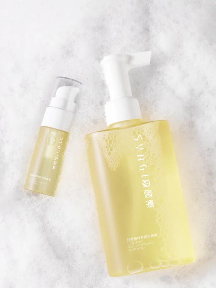 Two yellow skincare bottles with pump dispensers on a white marble surface