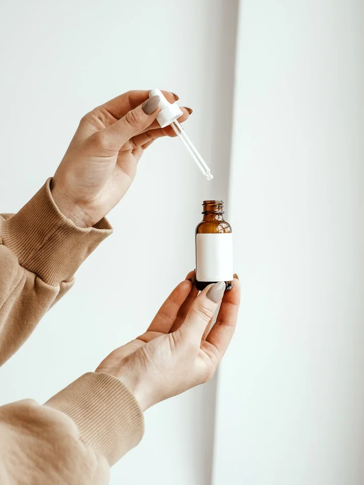 Close-up of hands holding a dropper bottle of serum, ready for application