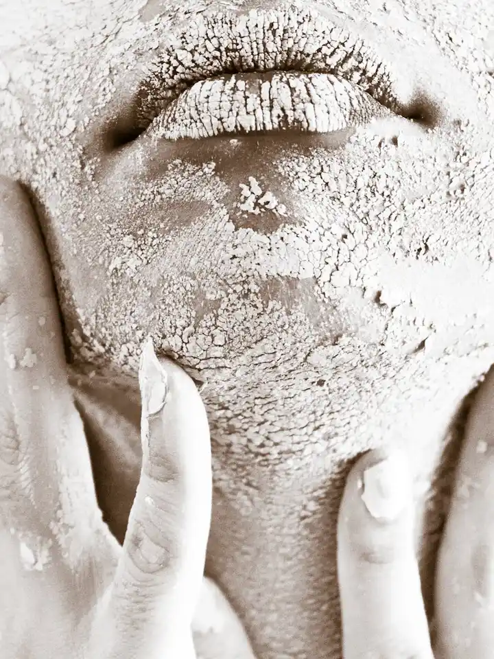 Close-up of a dry, flaky facial skin with a hand touching the cheek.