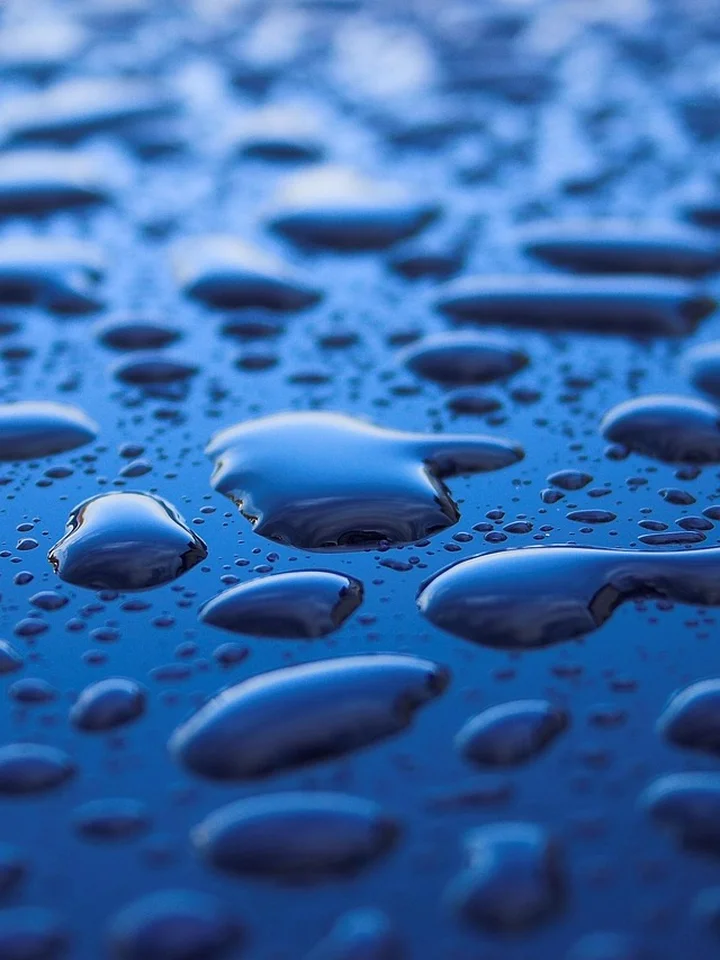 Close-up of blue water droplets on a glossy surface