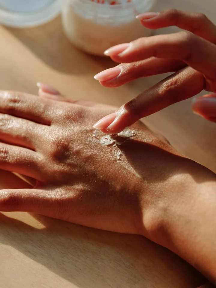 Close-up of hands applying a small amount of moisturizer on the skin, illustrating a non-comedogenic skincare routine.