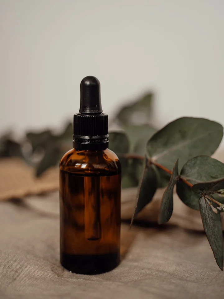 Amber glass dropper bottle on a neutral fabric with eucalyptus leaves in the background