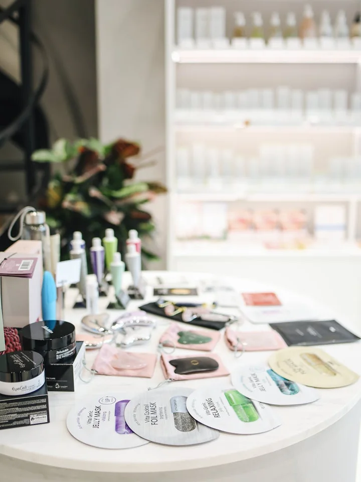 Assorted skincare and makeup products arranged on a white circular display table in a bright retail setting.
