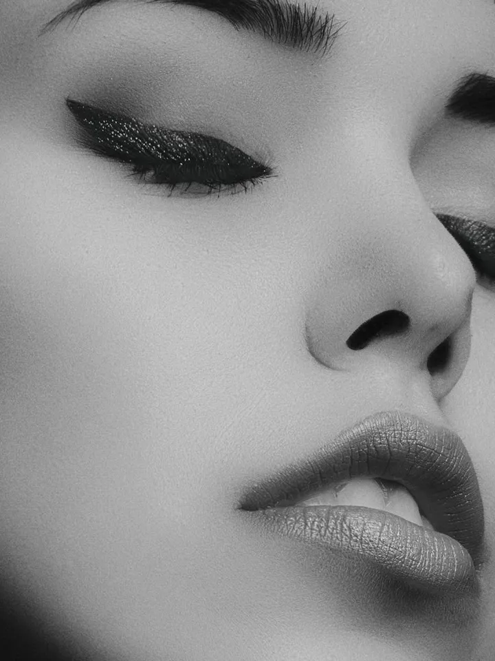 Close-up black-and-white portrait of a person wearing bold eyeliner and matte lipstick.