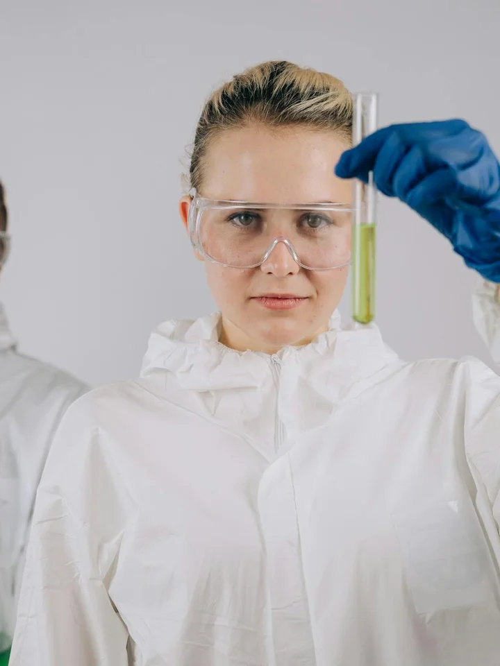 Lab scientist in protective gear holding a test tube, illustrating careful evaluation of skincare ingredients.