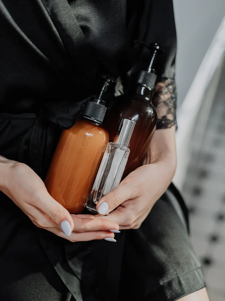 Close-up of hands holding amber glass bottles with droppers, skincare products for sensitive, acne-prone, or aging skin.