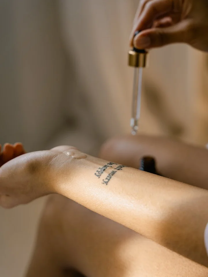 Close-up of a hand using a dropper to apply mandelic acid serum onto the forearm
