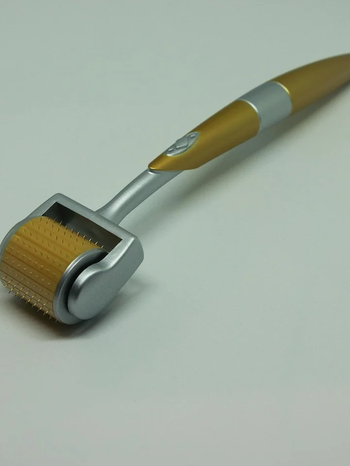 Close-up of a dermaroller microneedling device with a wooden handle and a spiked roller