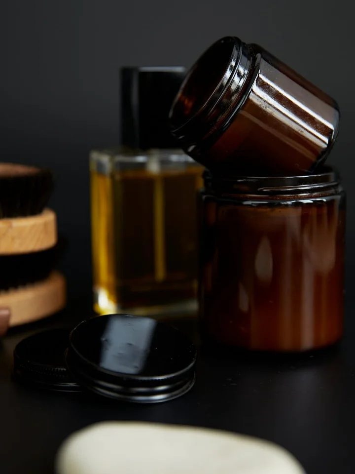 Close-up of brown glass peptide serum containers and a dropper on a dark surface, illustrating mixing and rotating strategies in skincare.