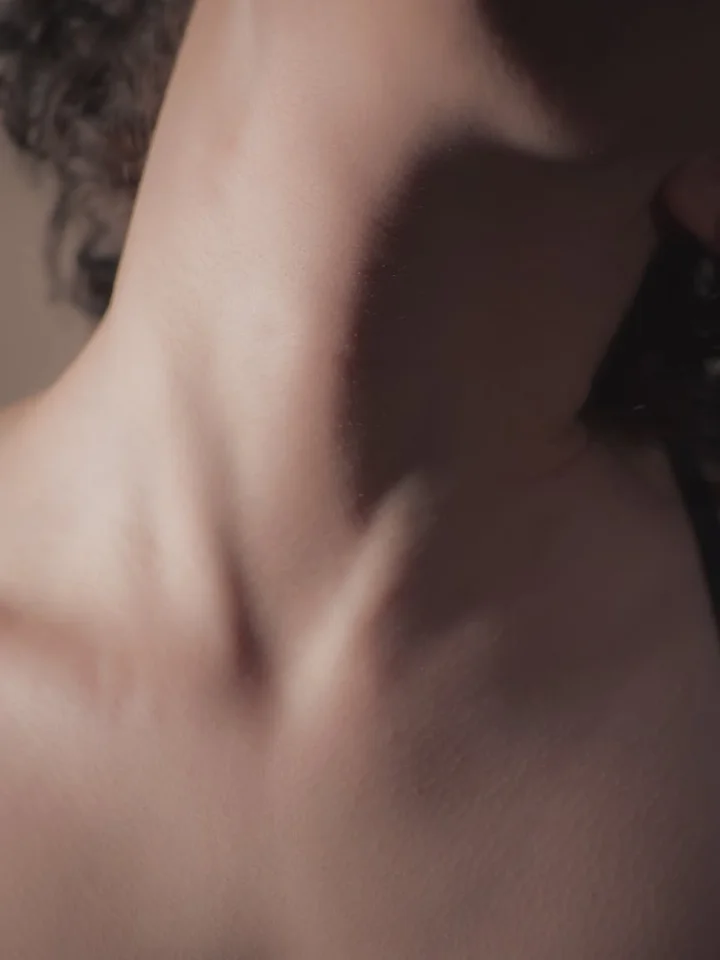 Close-up of a person's neck and upper chest showing skin texture and gentle contours.