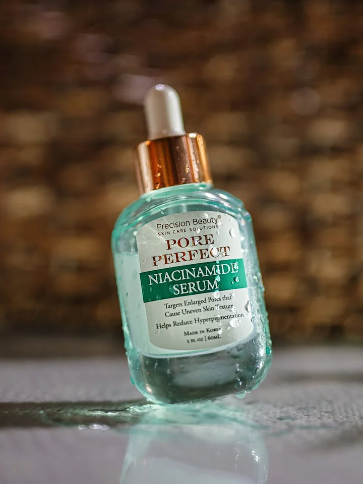 Dropper bottle of niacinamide serum with turquoise liquid, labeled Pore Perfect Niacinamide Serum