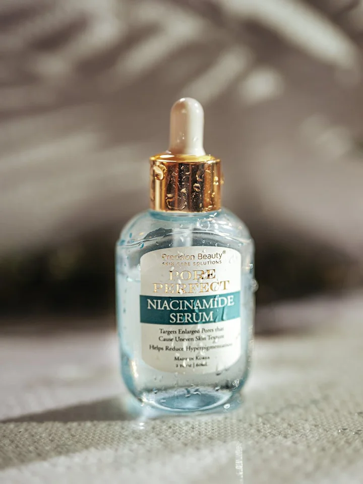 Small glass dropper bottle labeled Niacinamide Serum on a soft fabric background