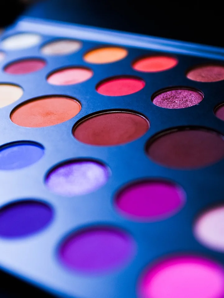 Close-up of a colorful makeup palette with round pans in blue, purple, pink, and orange tones.
