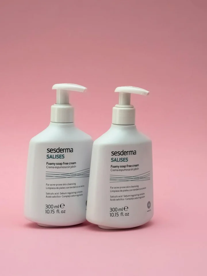 Two white pump bottles labeled Sesderma, placed side by side on a pink background.