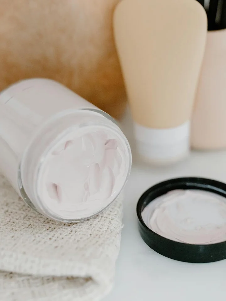 Cream jars and tubes on a soft textured cloth, representing skincare products for supporting the skin barrier.