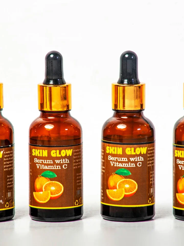 Amber glass dropper bottles labeled Skin Glow Serum with Vitamin C arranged in a row with orange slices on the label.