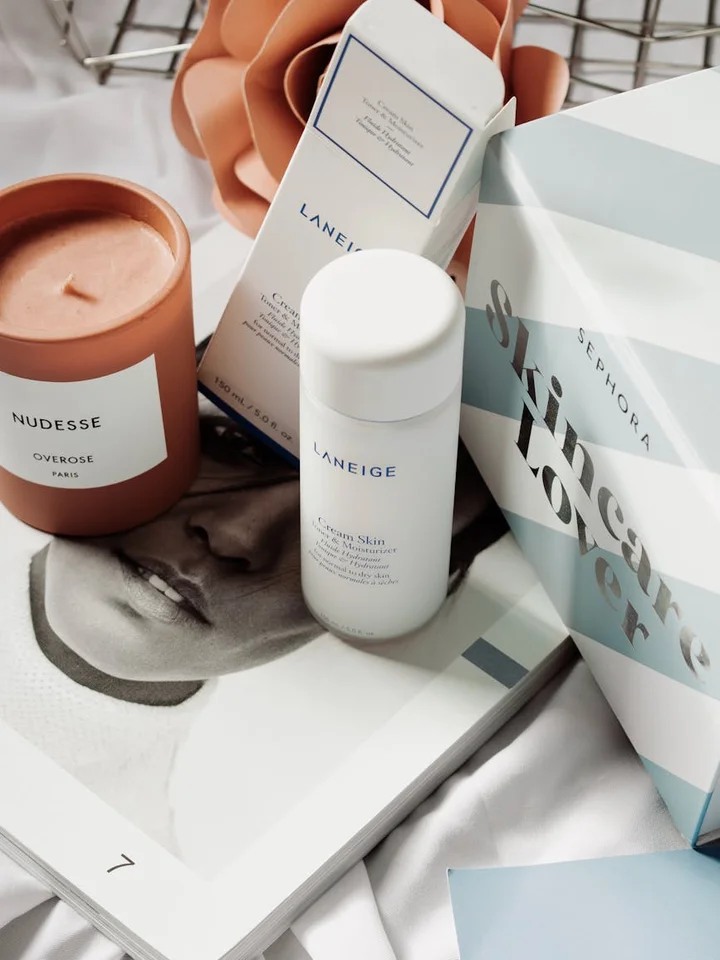 Assorted skincare products arranged on a magazine page, including a white Laneige bottle and boxed items