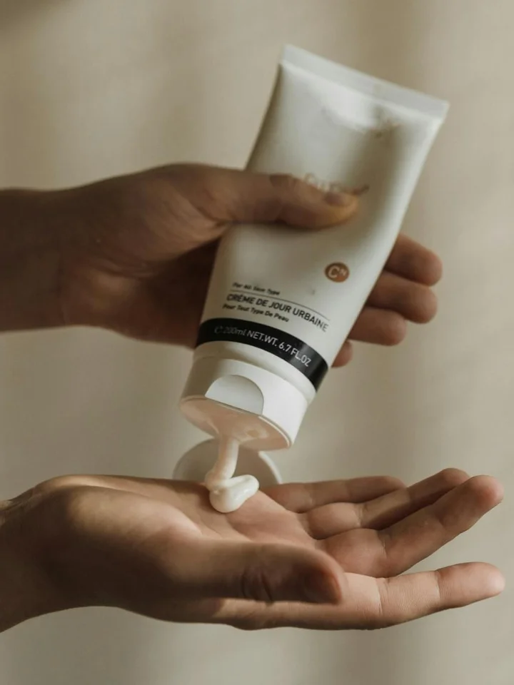 Hands holding a tube and squeezing a cream onto the palm