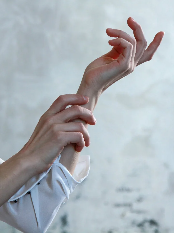 Close-up of a person's forearm and hands against a soft, neutral background, suggesting skin care analysis.