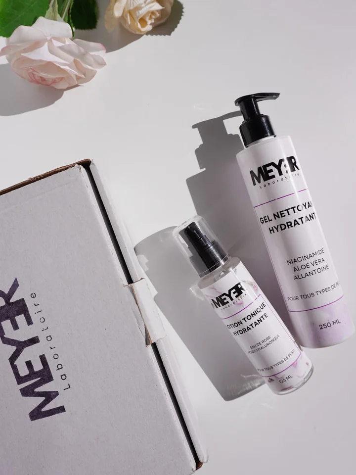 White skincare bottles and a white box arranged on a clean white surface.