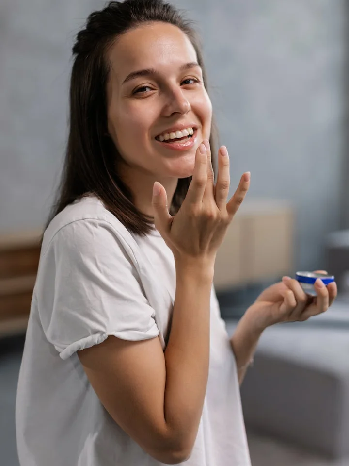 Smiling woman applying moisturizer to her face