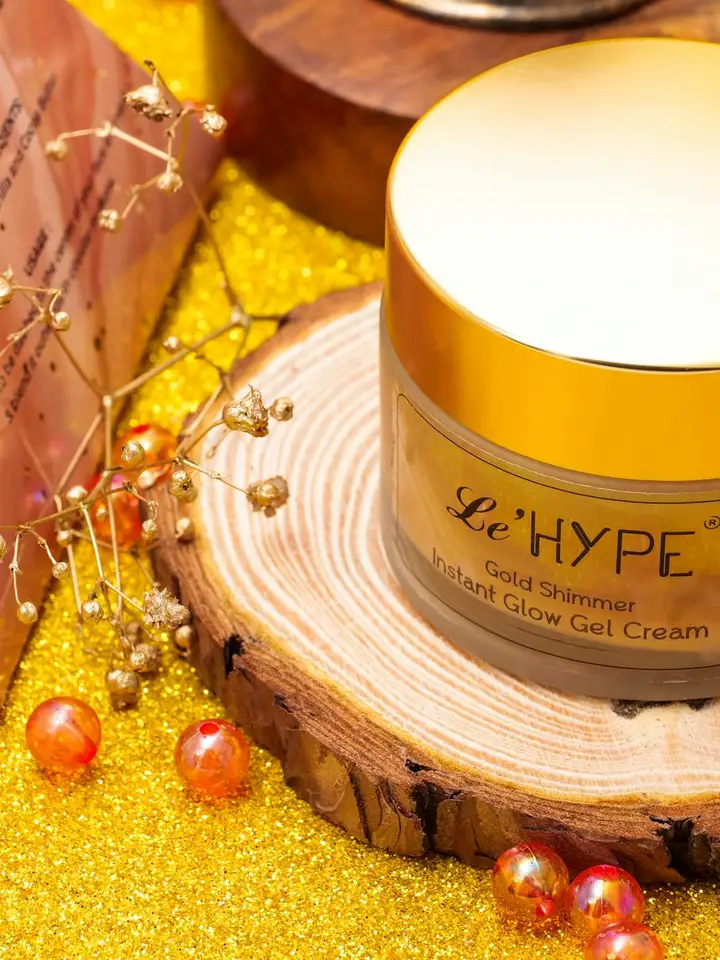 Close-up of a gold-lidded jar labeled Le'HYPE on a wooden coaster, surrounded by a glittery gold background
