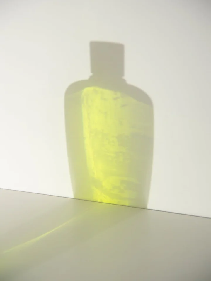 Yellow-tinted bottle casting a bright shadow on a clean white surface