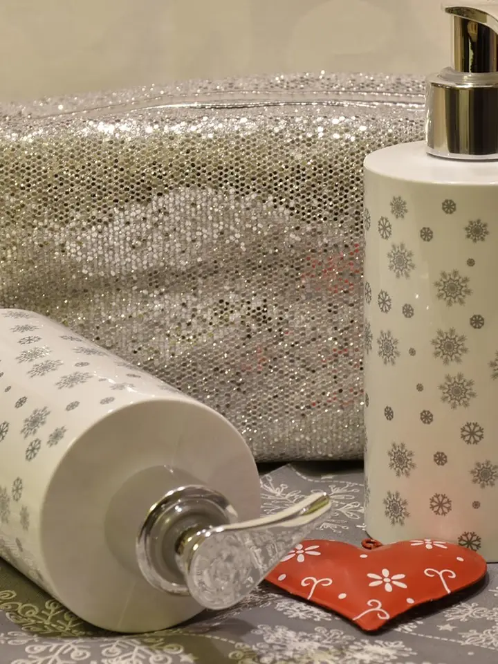 Assorted skincare bottles with pump dispensers on a silver patterned background, with a small red heart decoration.