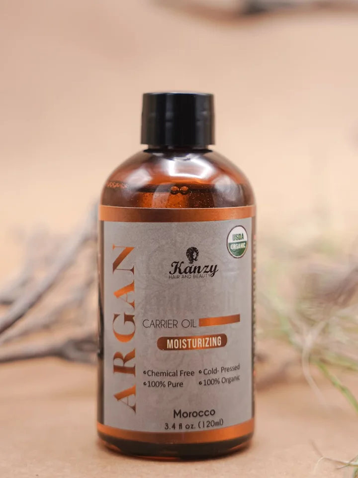 Amber glass bottle labeled 'Carrier Oil' (Argan) on a neutral beige surface with soft, natural background.