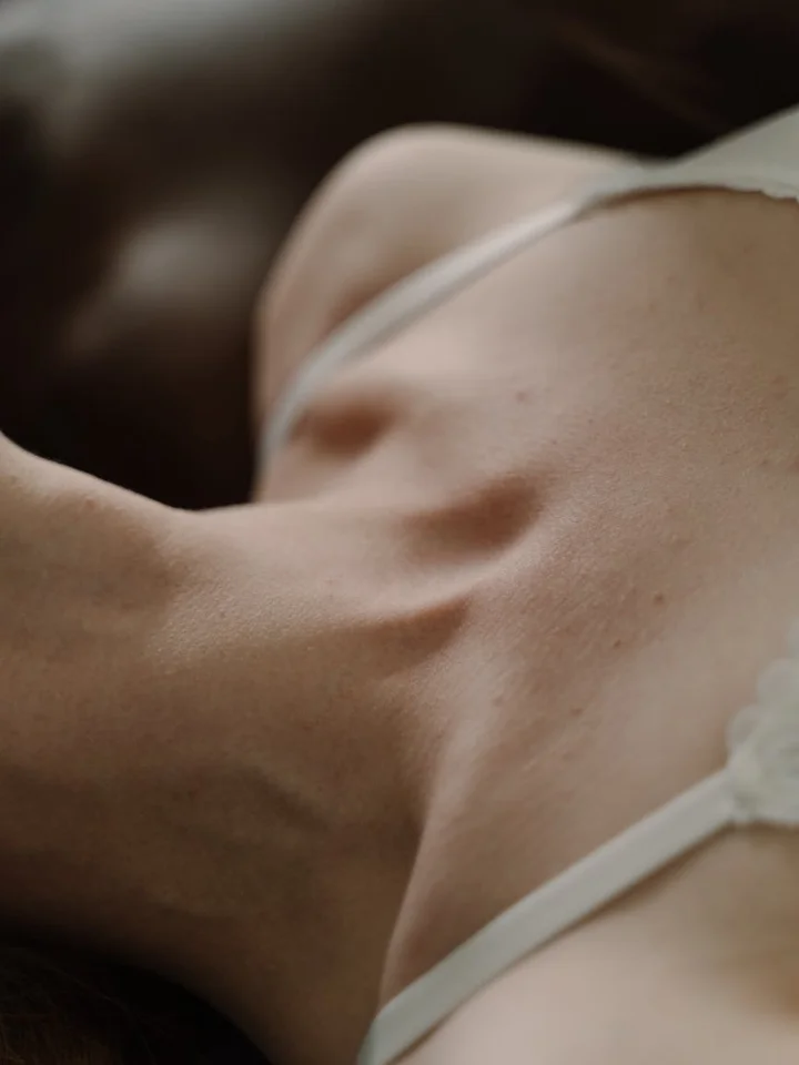 Close-up of a person’s back and shoulder wearing a light strap top