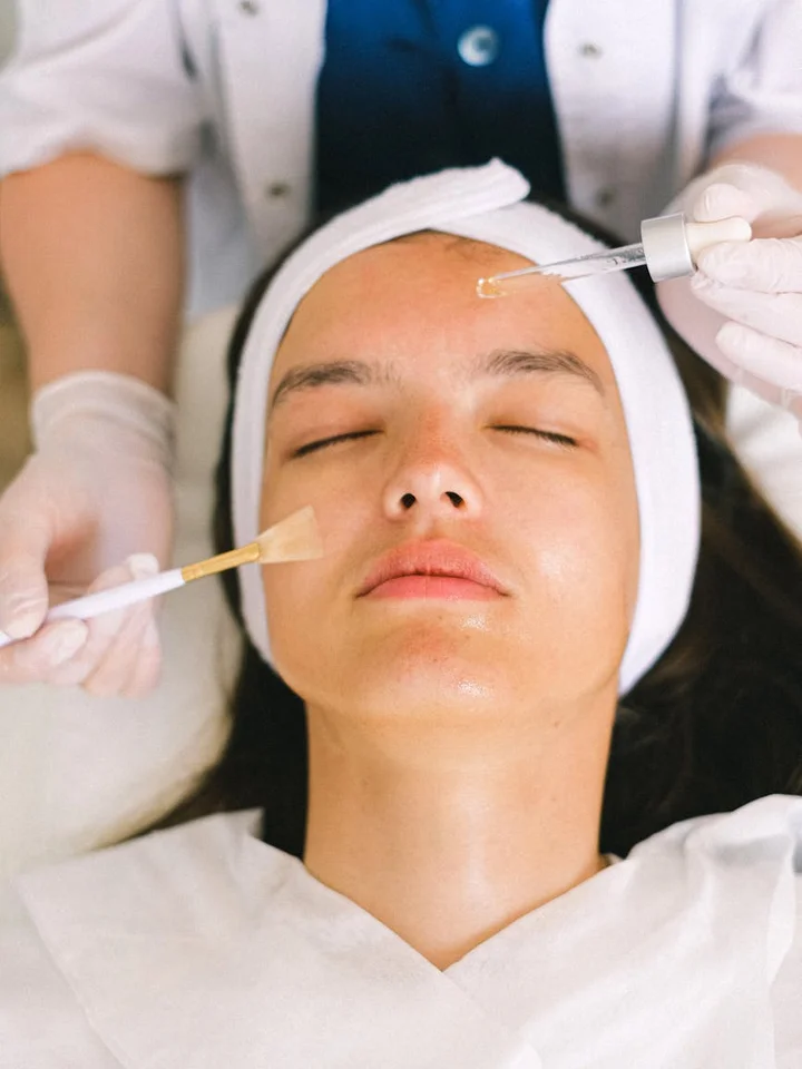 Close-up of a client receiving a facial treatment while a skincare professional uses a dropper to apply product to the face.