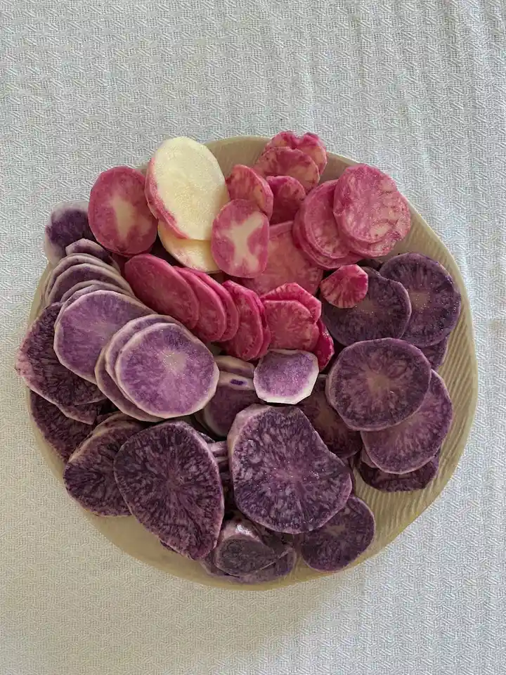 Plate of purple and pink taro chips on a light-colored fabric background