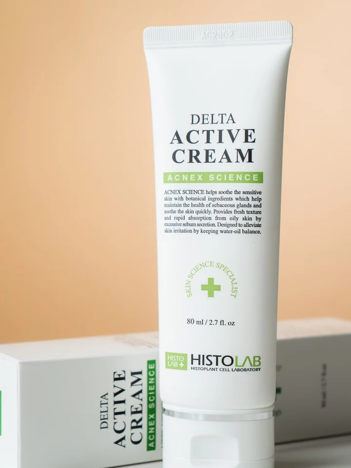 A white tube labeled 'Delta Active Cream' standing upright against a peach background.
