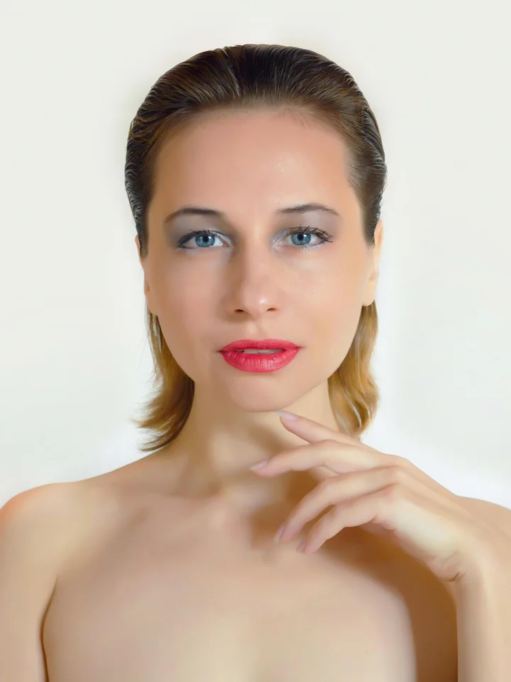 Portrait of a fair-skinned woman with light makeup looking at the camera, against a neutral background.