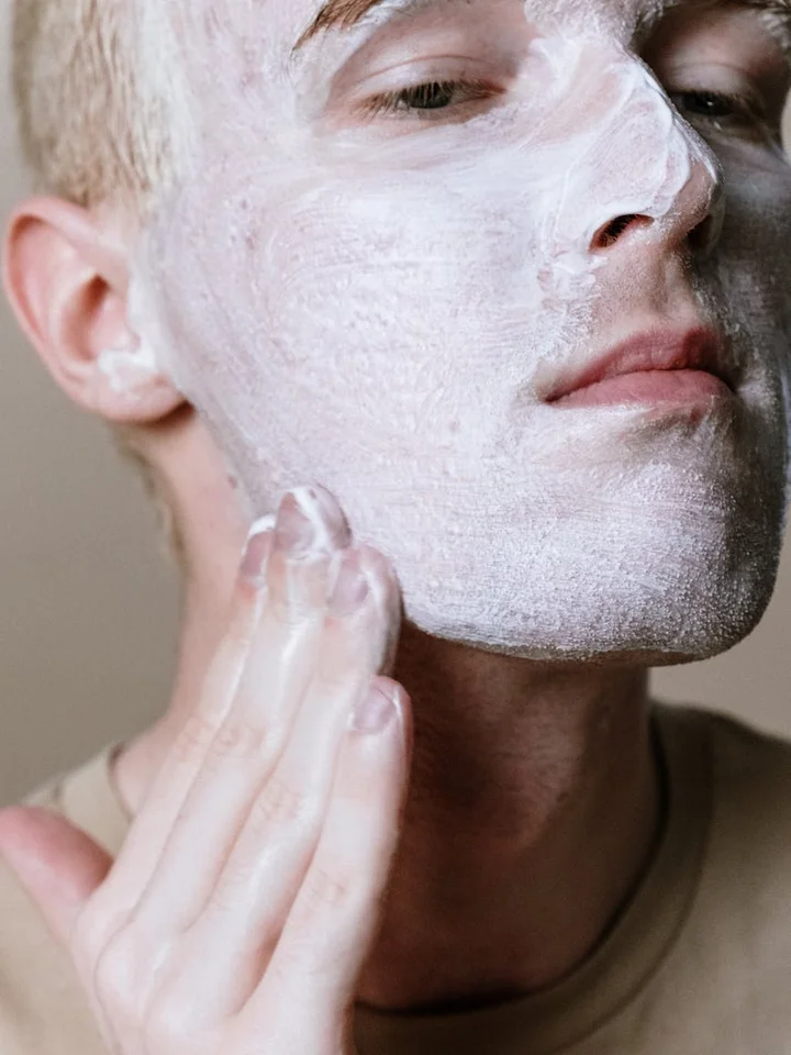 Person applying a white facial mask to their face