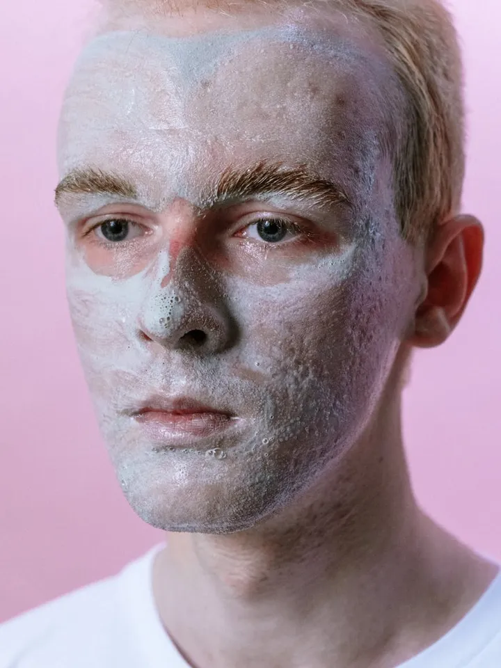 Person with a white facial mask applied during a skincare routine