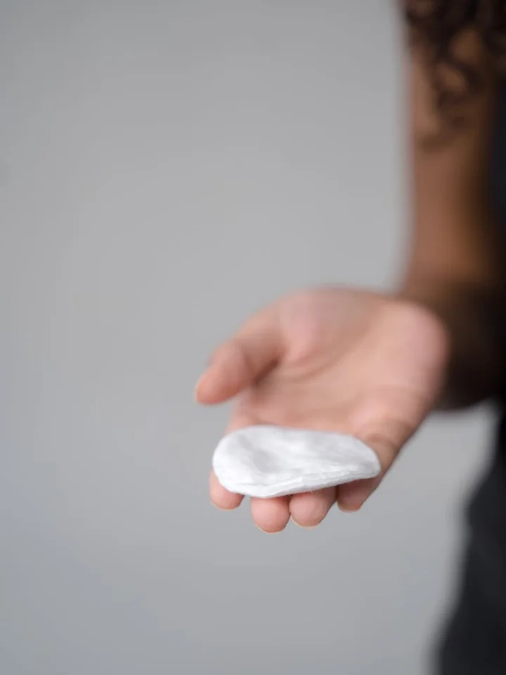 A close-up of a hand holding a cotton pad, ready for skincare application.