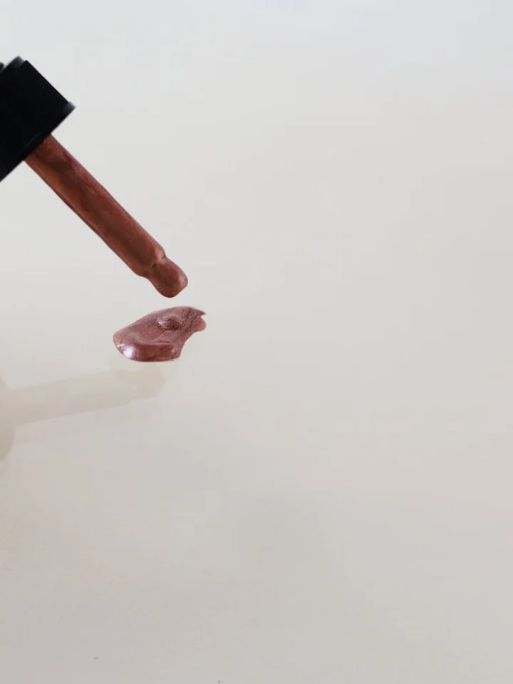 Dropper releasing a pink hyaluronic acid serum onto a white surface