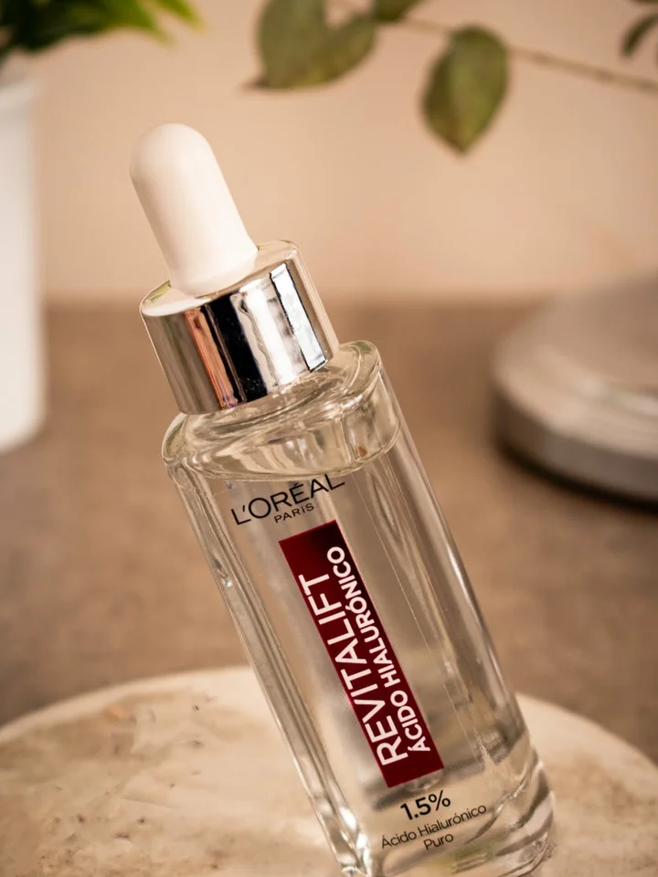 Close-up of a glass dropper bottle labeled L'Oreal Paris Revitalift Hyaluronic Acid Serum on a neutral countertop, highlighting a gentle, hydrating acid product for sensitive or eczema-prone skin.
