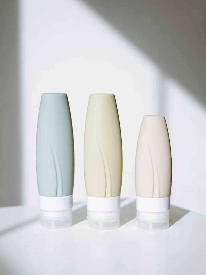 Three pastel-colored skincare bottles on a white surface.