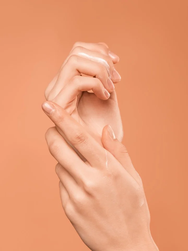 Close-up of hands with smooth skin against a peach-colored background, suggesting gentle skincare and barrier protection.