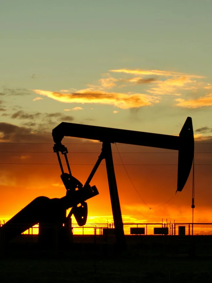 Silhouette of an oil pumpjack against a vibrant sunset sky