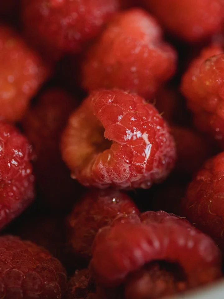 Close-up of ripe raspberries with rich red color and textured surfaces.