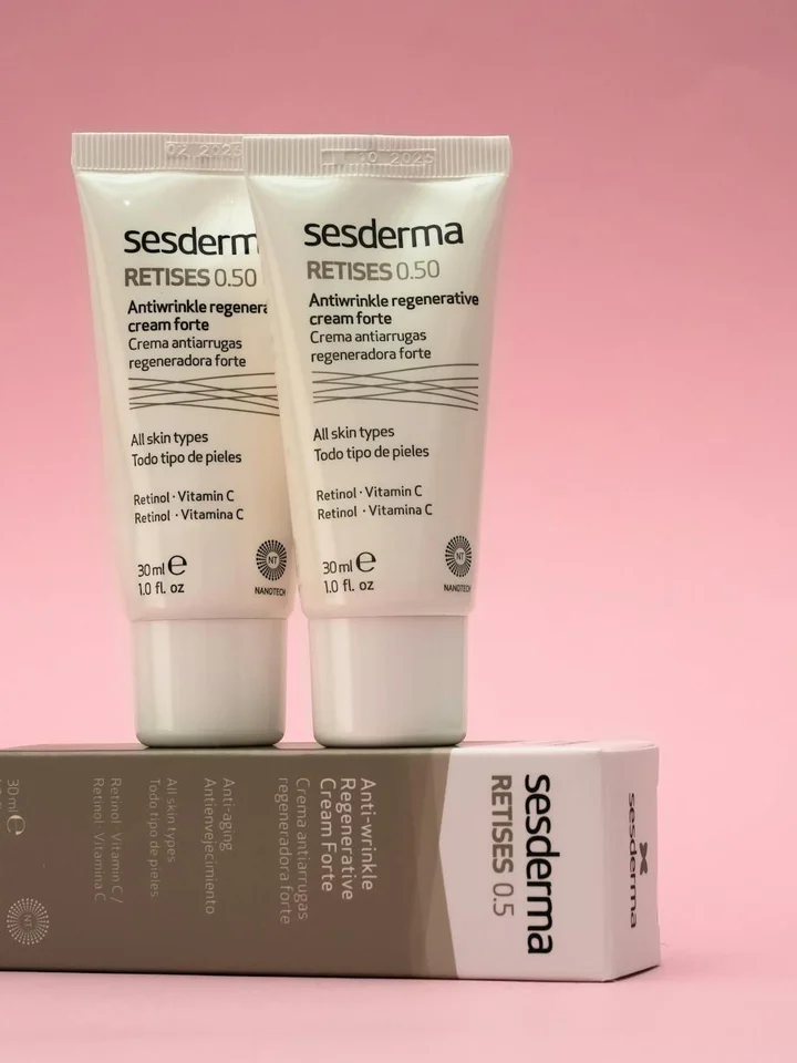 Two Sesderma Retises 0.5 retinol cream tubes standing upright against a pink background, with the box laid nearby.