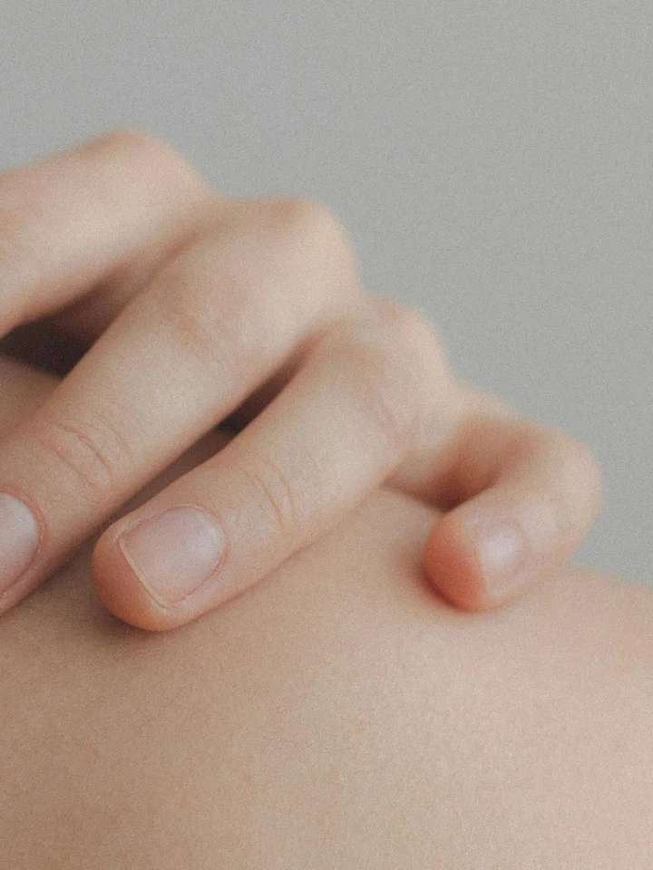 Close-up of a hand touching skin, illustrating the skin surface where chemical exfoliants act
