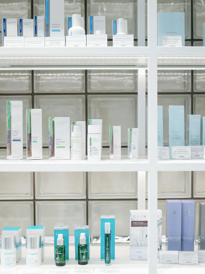 Assorted skincare products arranged on white display shelves in a store.
