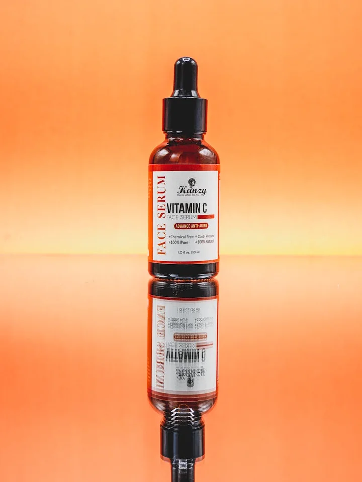 Amber glass dropper bottle on a glossy orange surface with a reflective finish, a skincare serum container ready for use
