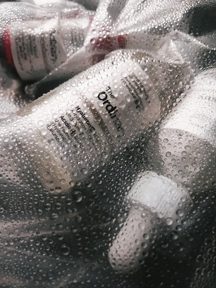 Close-up of a bottle labeled The Ordinary amid condensation on a surface, symbolizing a skincare routine for body acne