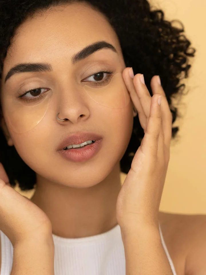 Close-up of a woman applying skincare product near the under-eye area, highlighting caution with sensitive skin.