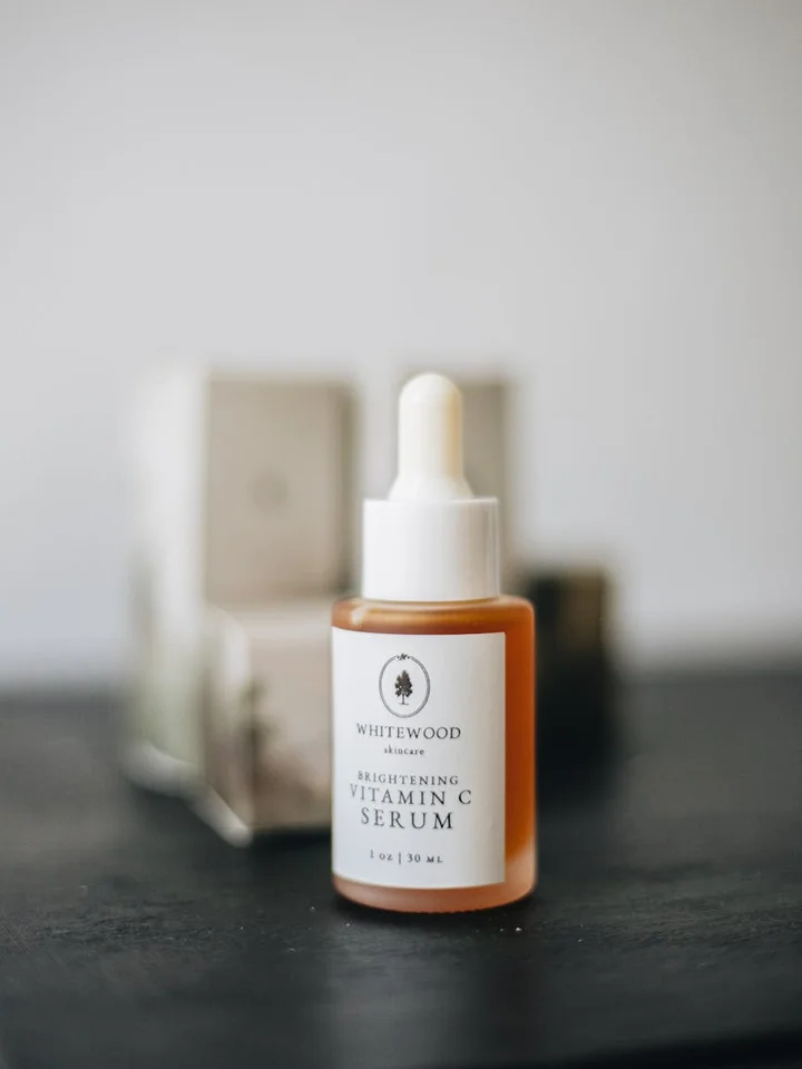 Amber glass bottle of Brightening Vitamin C Serum with dropper, blurred background